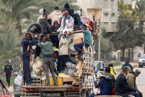 People evacuating from a tent camp ride in the back of a truck with belongings as they flee from Rafah in the southern Gaza Strip on February 13, 2024 taking the coastal road north towards the centre of the Palestinian territory amid the ongoing conflict between Israel and the Palestinian militant group Hamas. (Photo by MOHAMMED ABED / AFP)