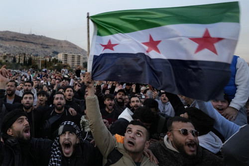 Syrian citizens wave the revolutionary flag and shout slogans, as they celebrate during the second day of the take over of the city by the insurgents in Damascus, Syria, Monday, Dec. 9, 2024. (AP Photo/Hussein Malla)